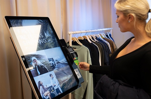 Woman using a touch screen in a store; copyright: Elo Touch Systems...