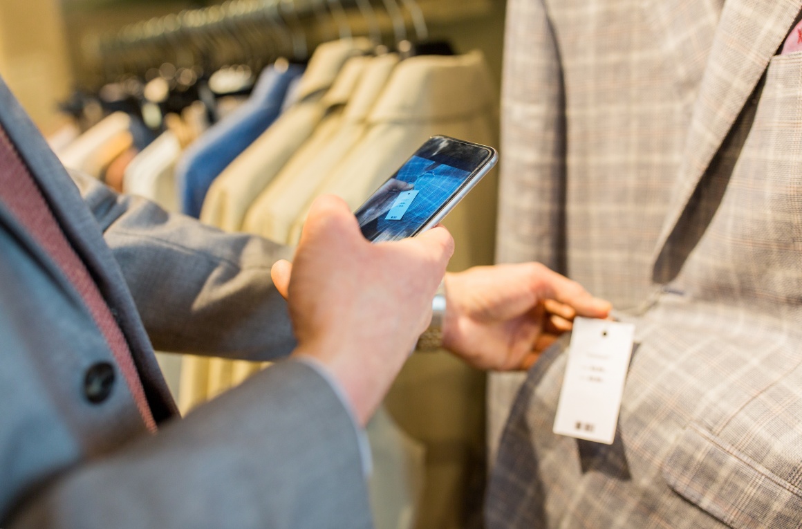 Person photographs price tag on jacket with smartphone; copyright:...