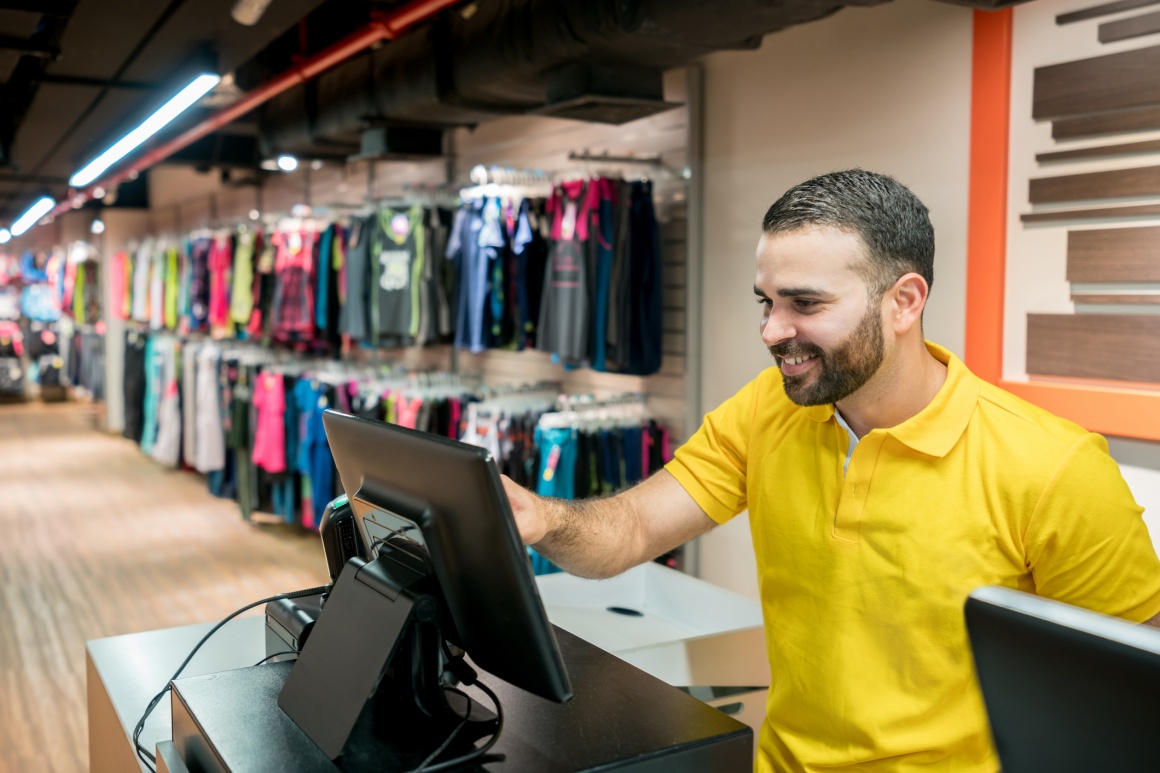 Laughing sales man at a cash register; copyright: GettyImages/APG...