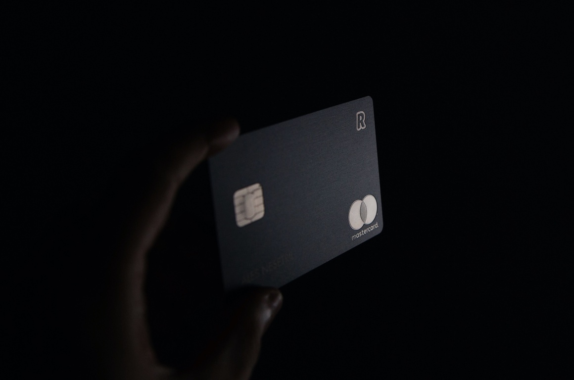 Credit card in a hand on black background
