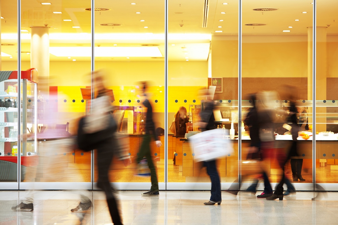 Silhouettes of people walking in front of a glass facade; copyright:...