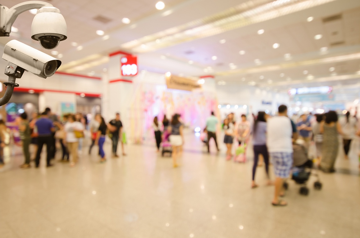 Surveillance cameras in a shopping center with lots of customers in the...