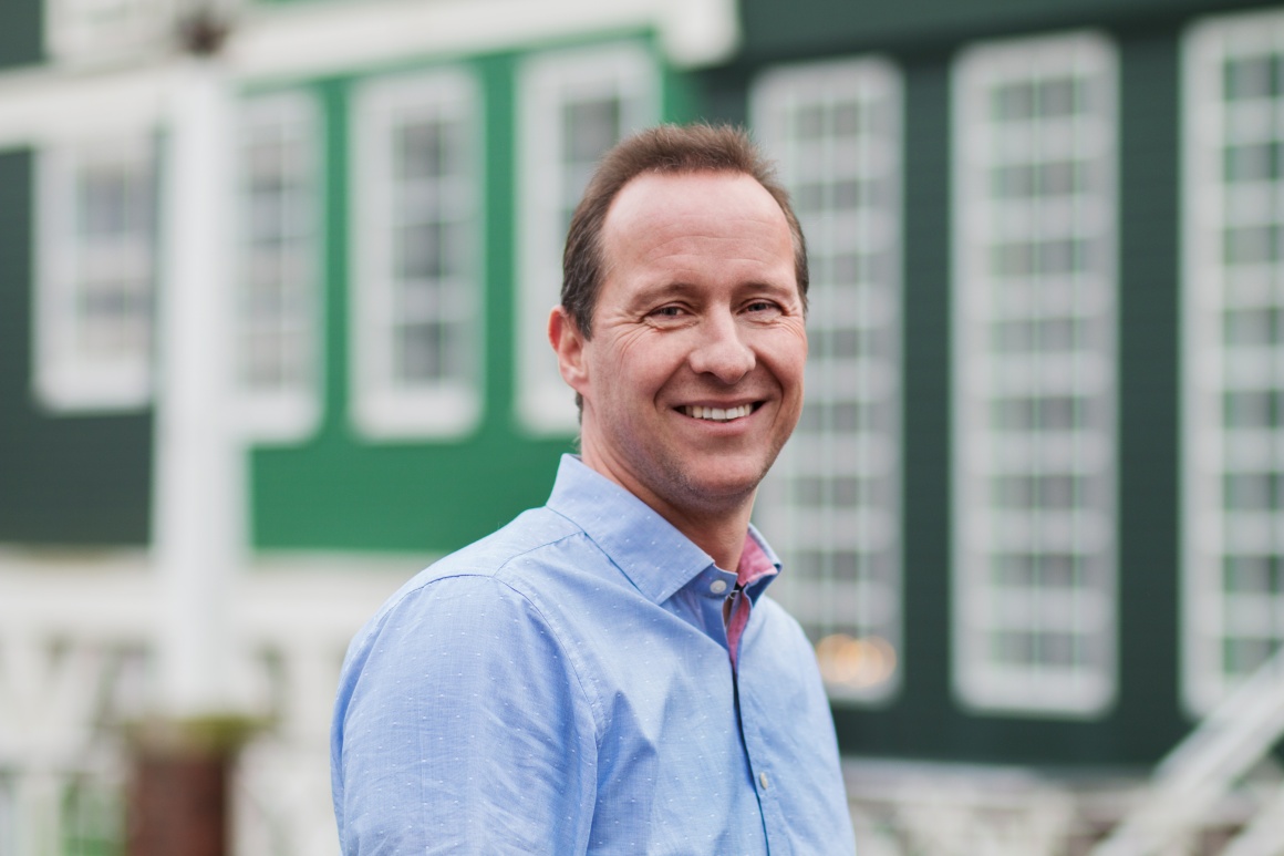 Man in light blue shirt smiles into camera