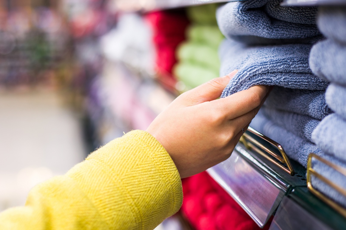 Hand taking a towel out of a stack of towels in a store; copyright:...