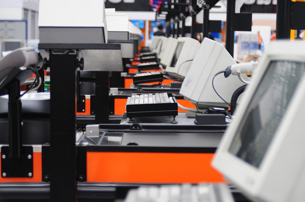 A long row of cash registers with monitors and other devices; copyright:...