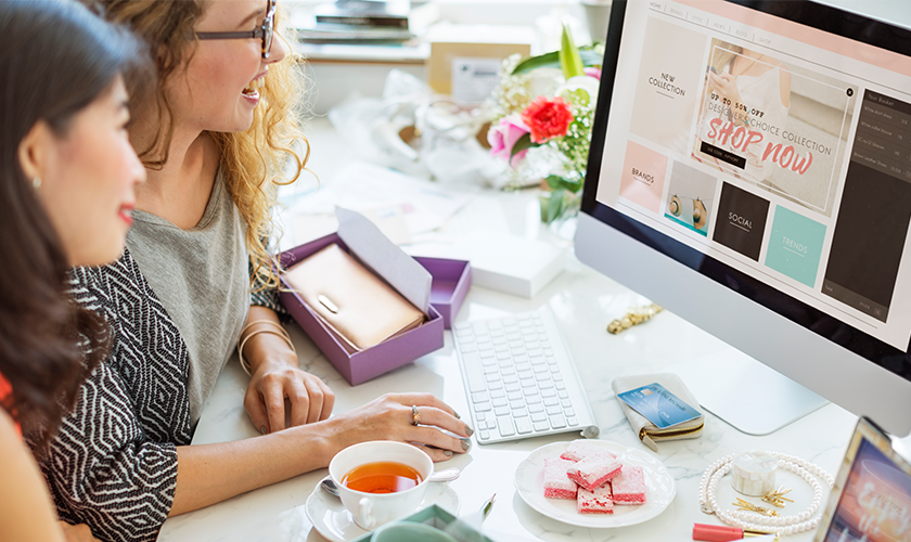 two women sitting in front of the computer shopping online....