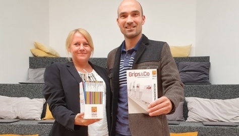 Woman and man hold program booklets in the camera.