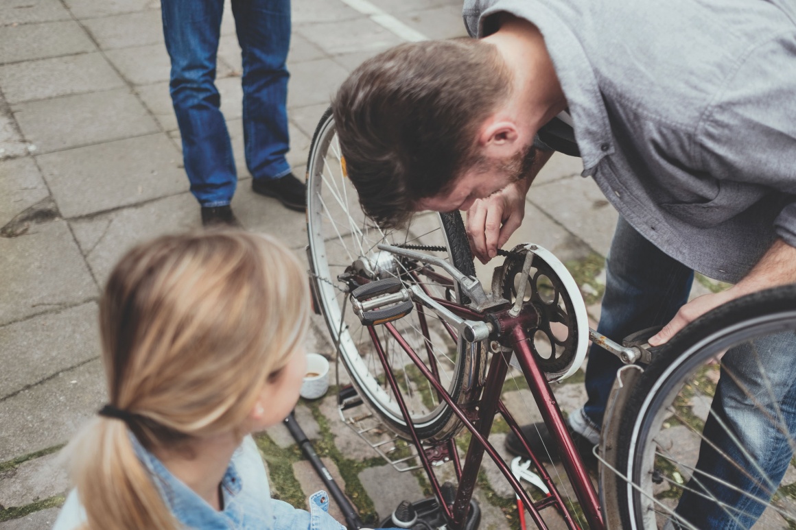 Man helps woman fix a bike.