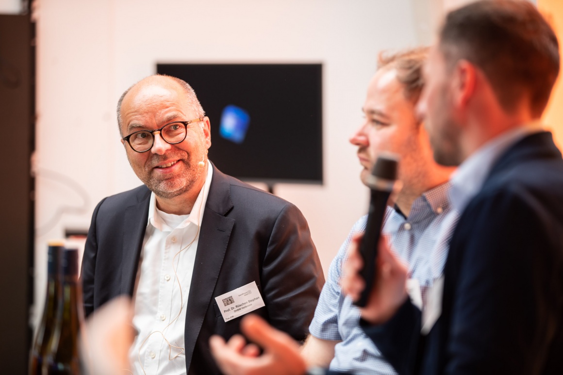 View of a smiling man listening to two other men talking....