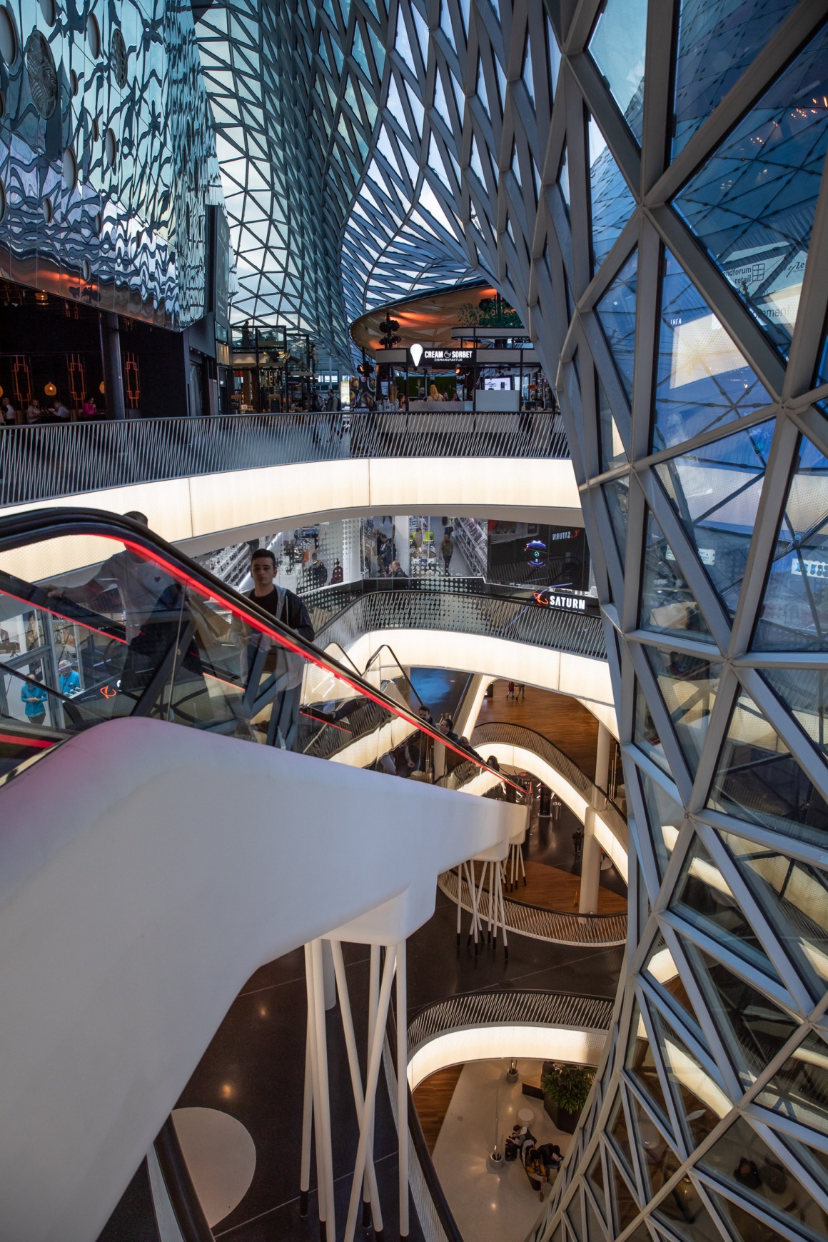 View into a shopping mall with several floors and elevators and glass walls...