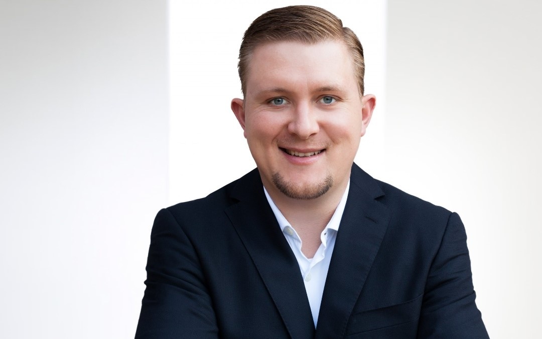 Man in suit smiles frontally into camera