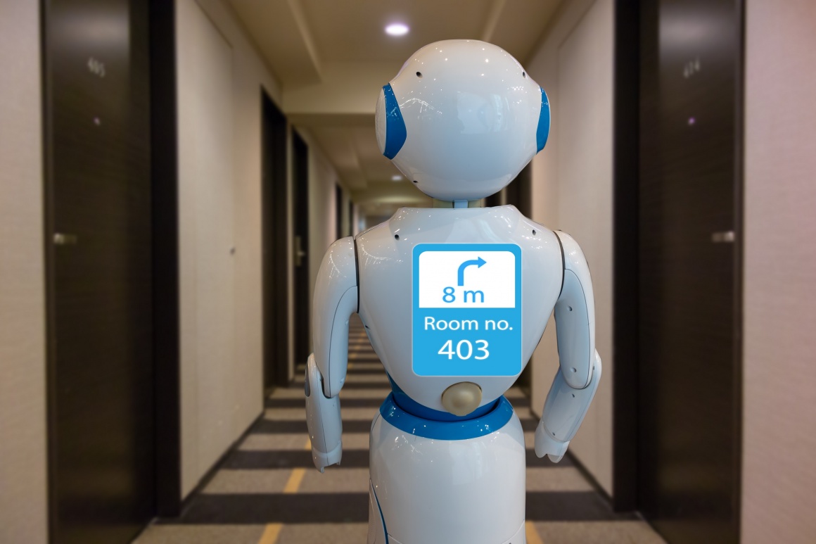 A white humanoid robot with a screen in the corridor of a hotel...