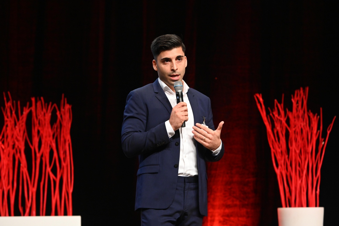 A man stands on a stage and speaks into a microphone...