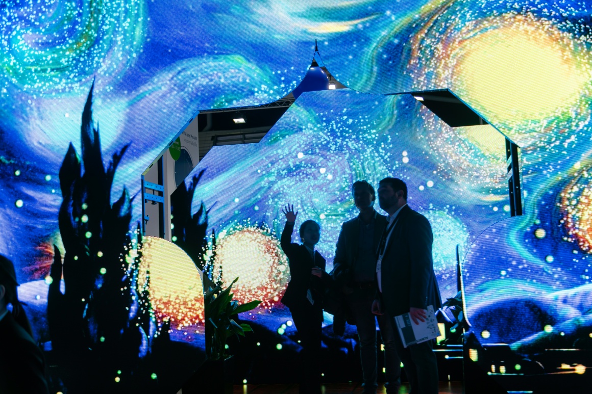 Three people standing in front of a futuristic wall....