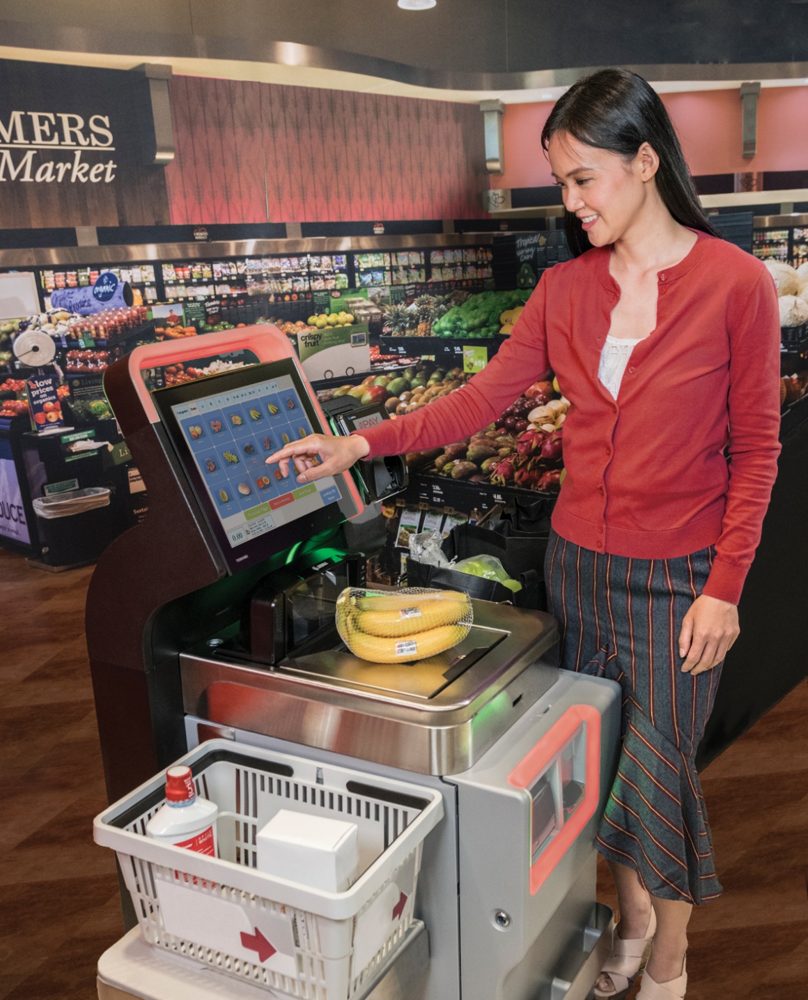 A woman is standing at a self-service checkout in the supermarket and typing on...