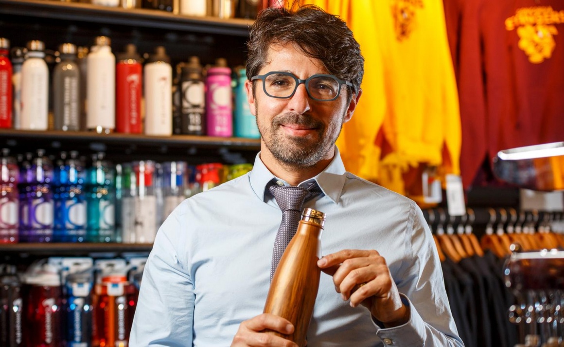 A man with glasses holding a bottle in his hands