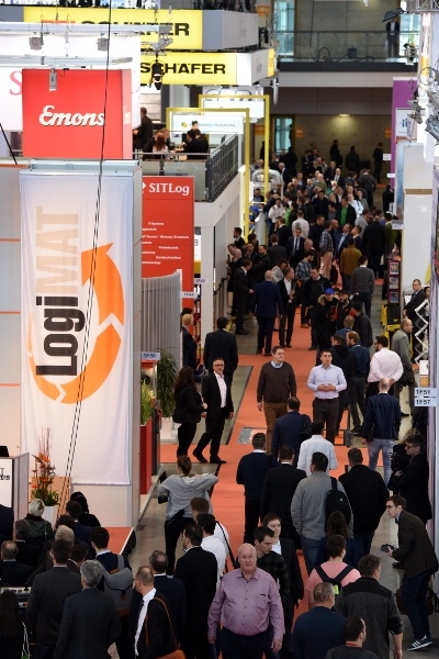 Visitors in an exhibition hall; on the left a logo from the LogiMAT exhibition...