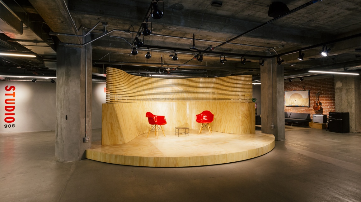 An empty warehouse room with a small stage and two red chairs...