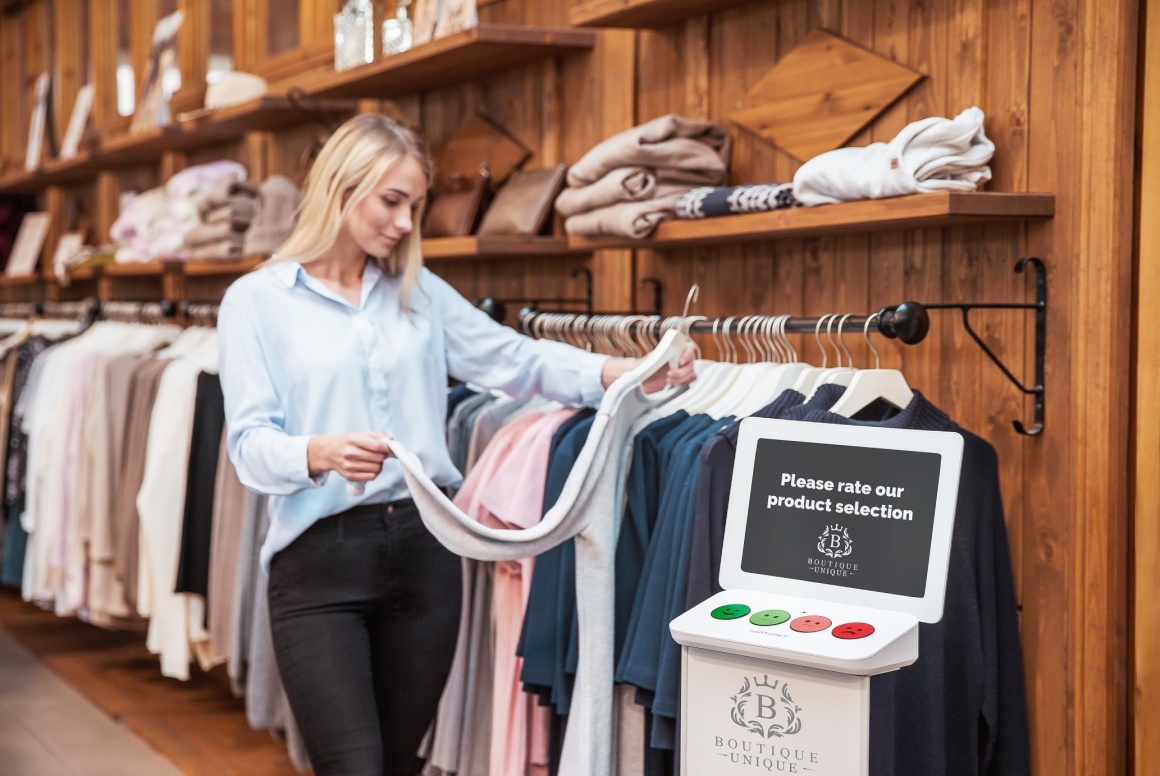 A woman in a clothing shop; in front of her a terminal where she can indicate...