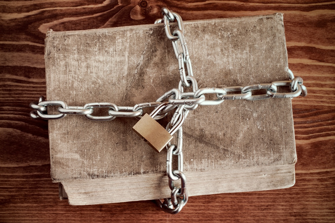 An old book locked with a chain and a padlock.