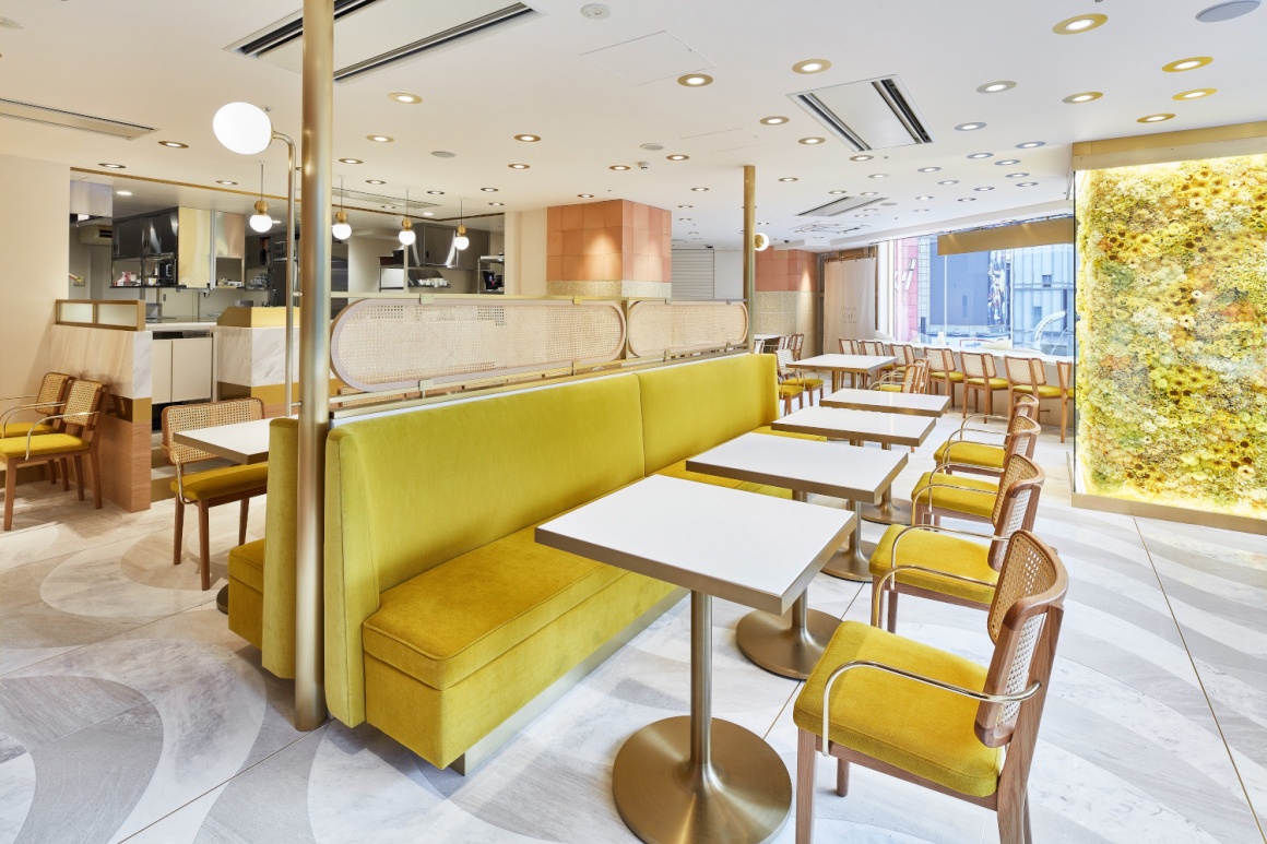 a view into a modern designed café with tables and chairs with yellow colours...