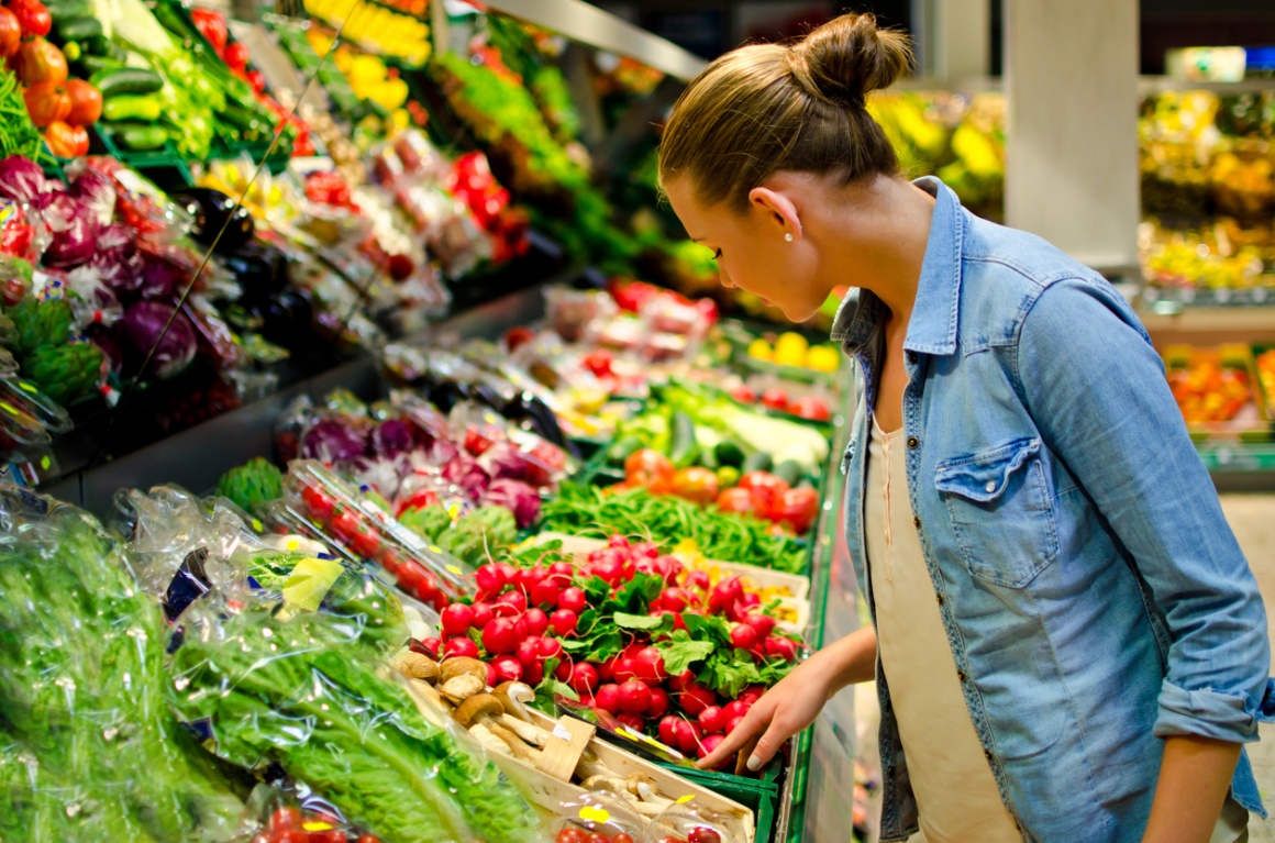 FrWoman standing in front of fruit and vegetable shelf in supermarket
au steht...