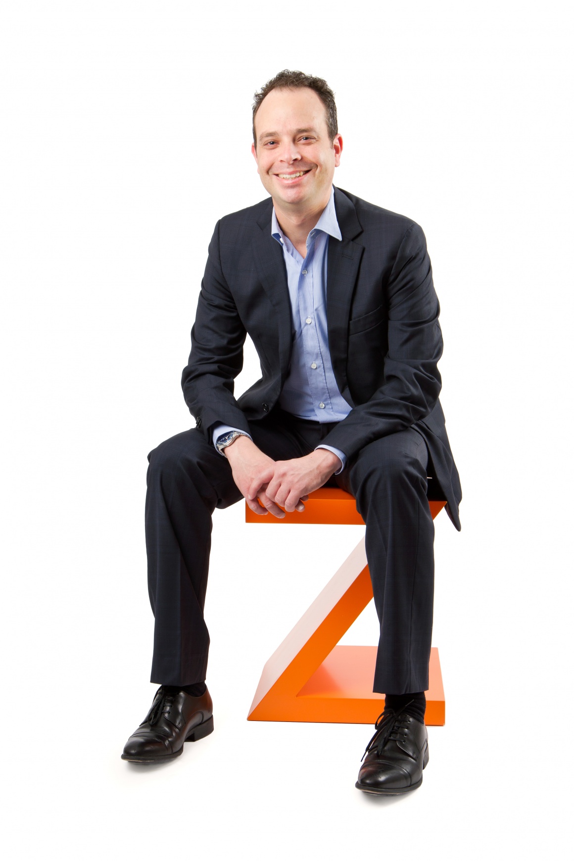 Man sitting on big orange Z against white background....