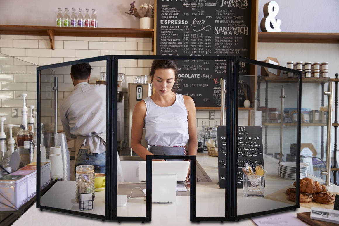 A young woman behind a counter in a gastronomical institution behind a...