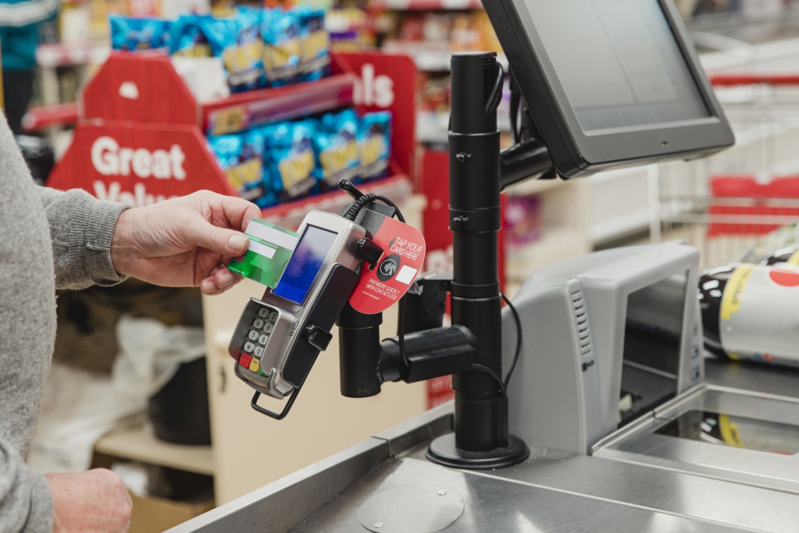 A man pays contactlessly at the supermarket checkout...