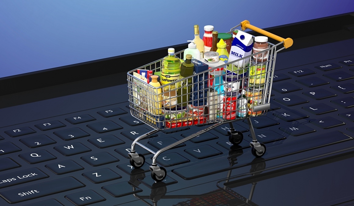 A full mini shopping cart is on the keyboard of a laptop...