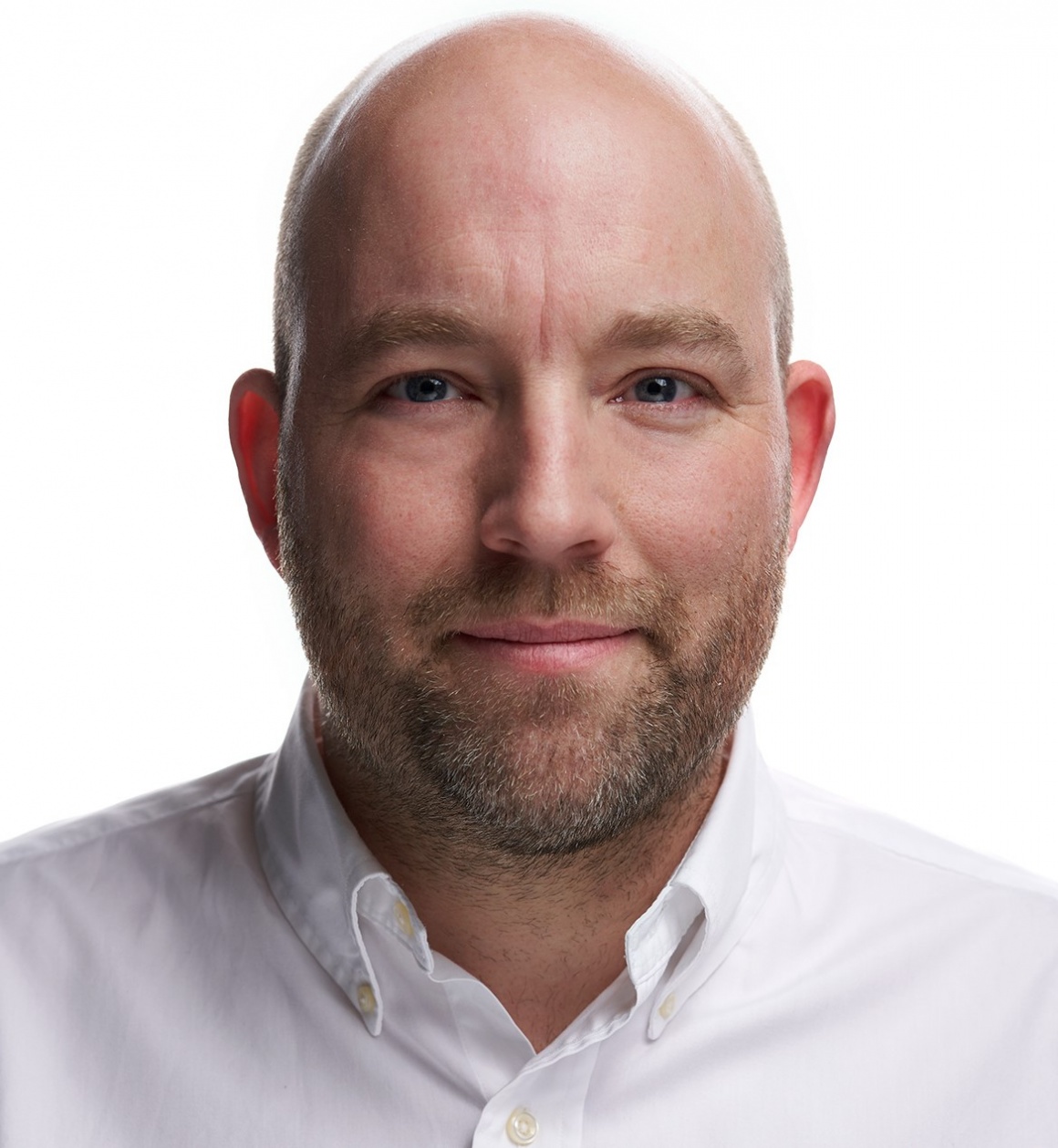 A man in a white shirt smiles into the camera