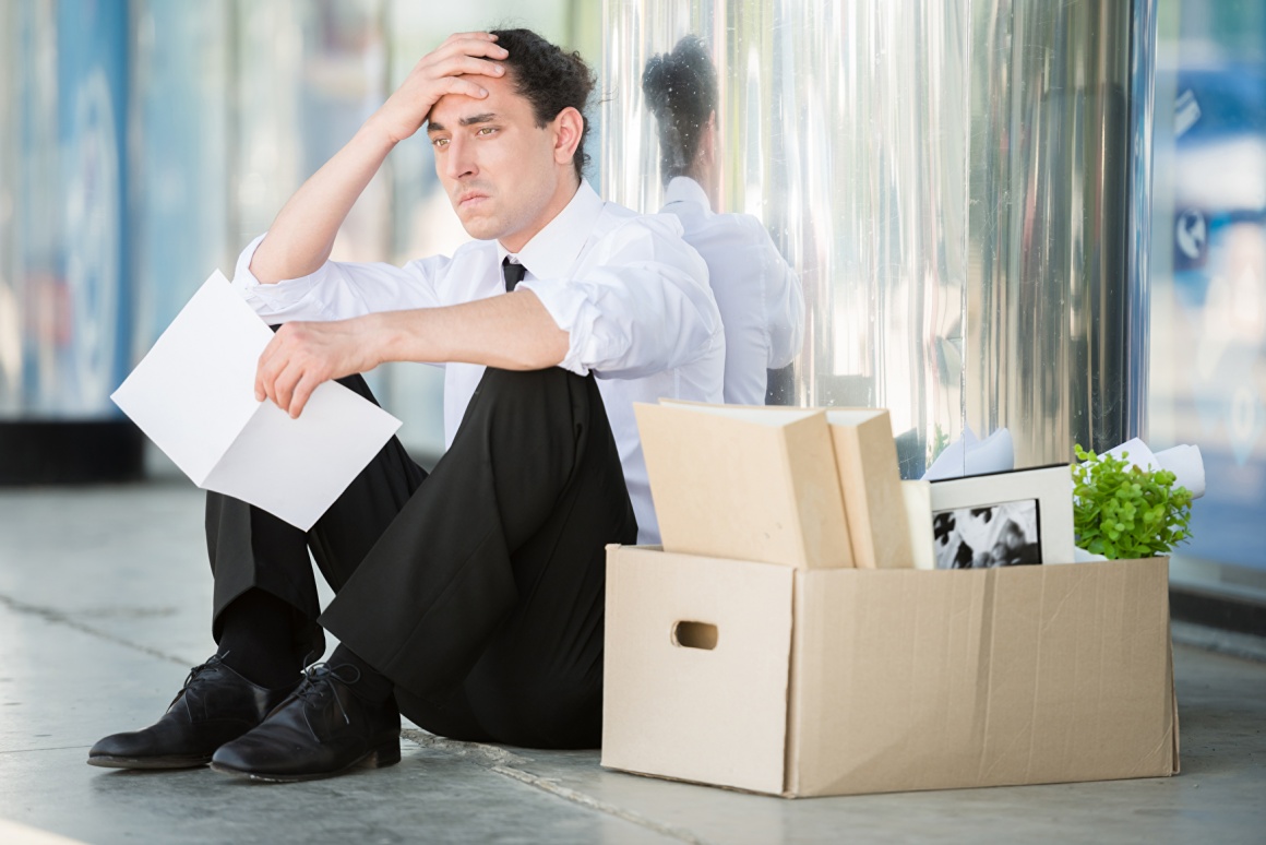 A man is sitting outside next to several boxes