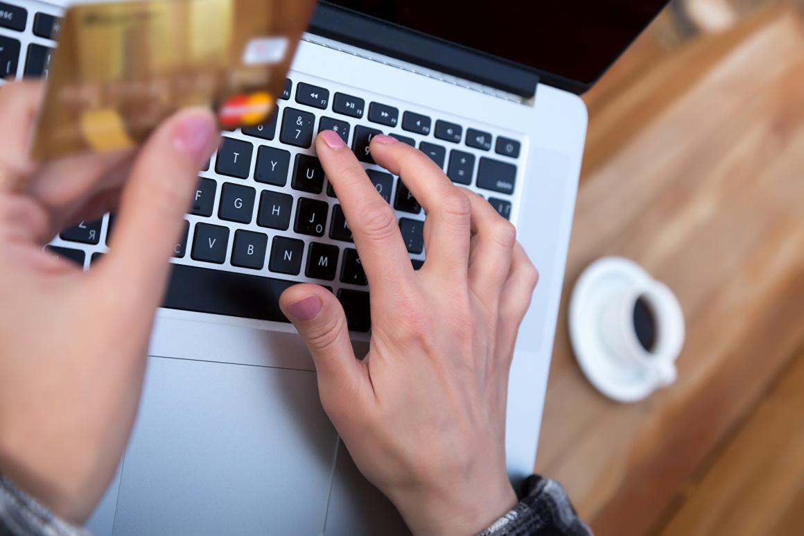 A person holding a mastercard while working on a laptop...