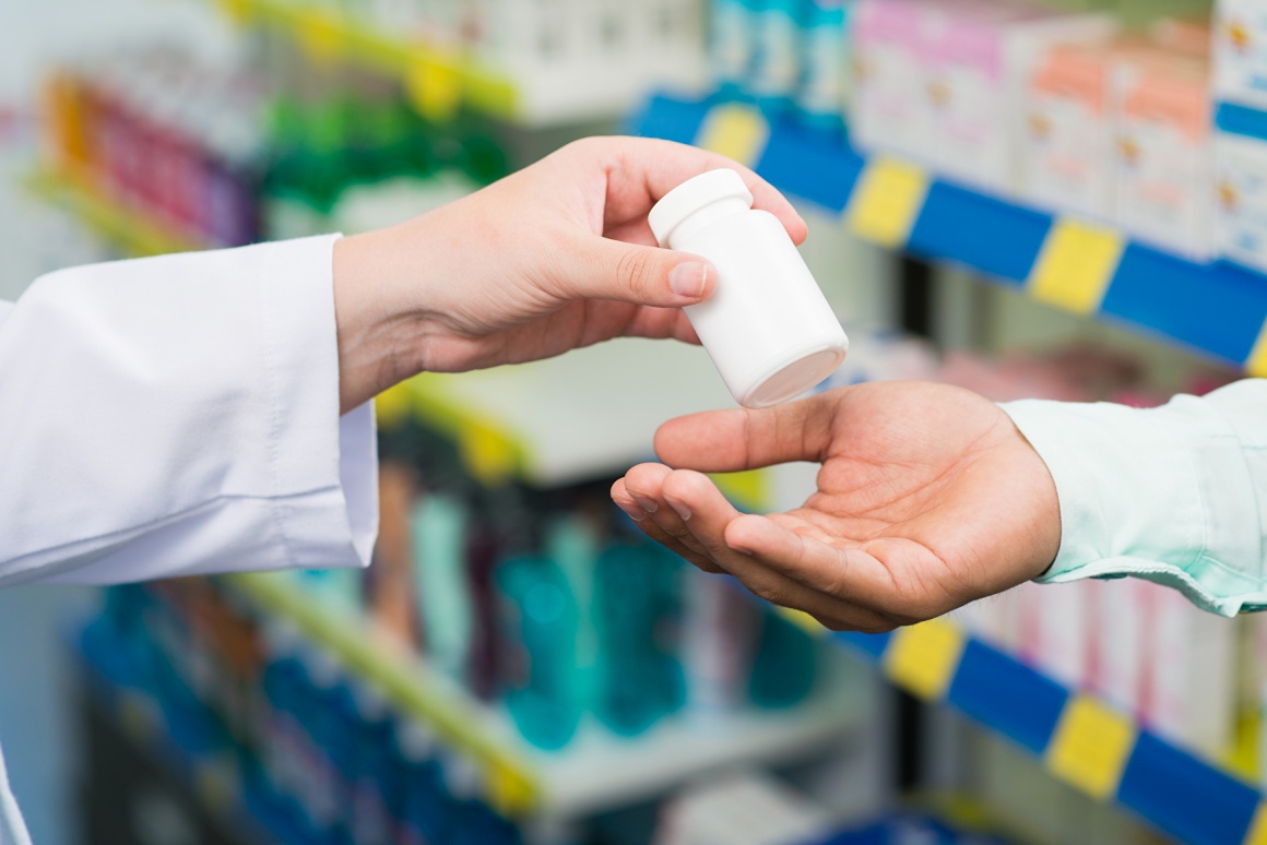 Pharmacist hands a small package of pills to someone...