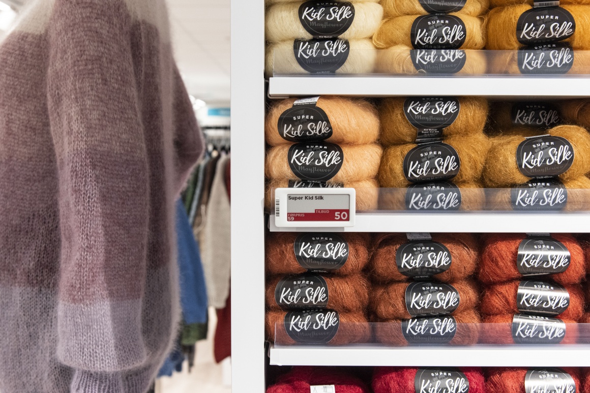 A shelf with wool varieties in the shop and a mannequin in a wool sweater...