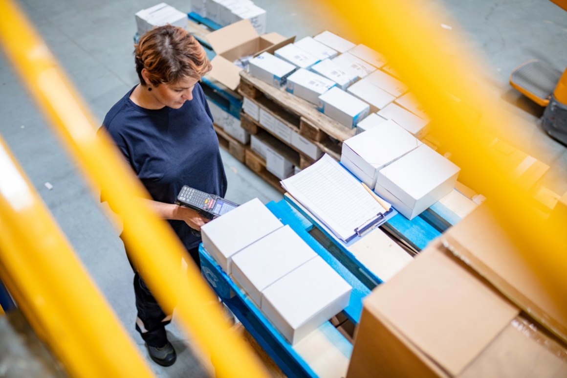 A woman working in a warehouse scanning packages