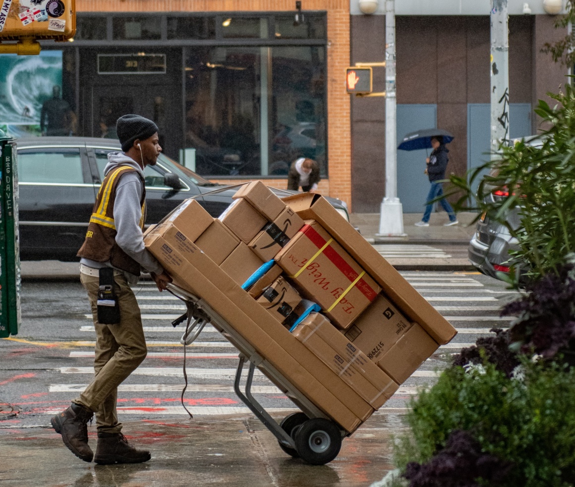 A parcel service employee drives a cart with many parcels along a road...