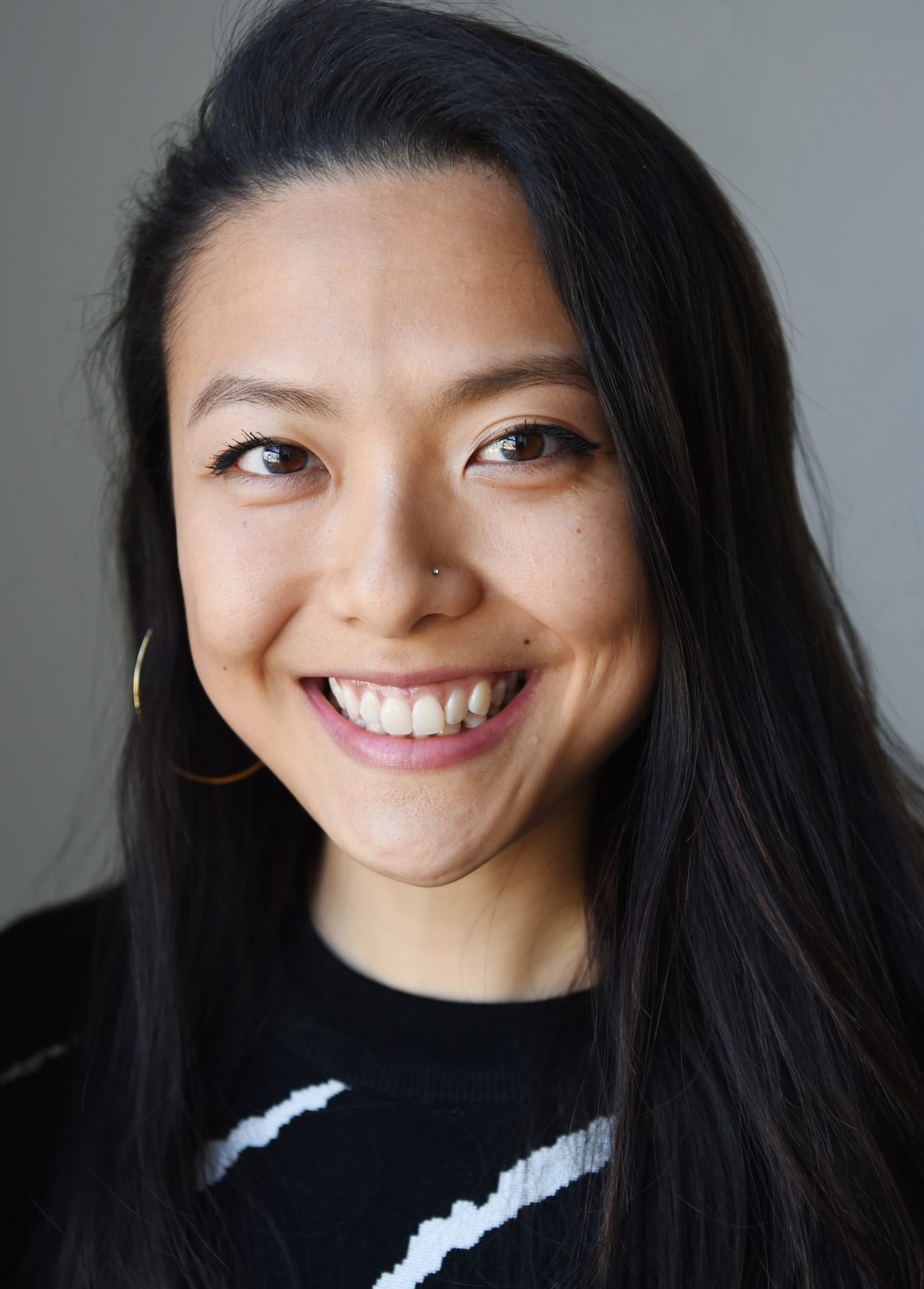 A woman with long dark hair smiles into the camera