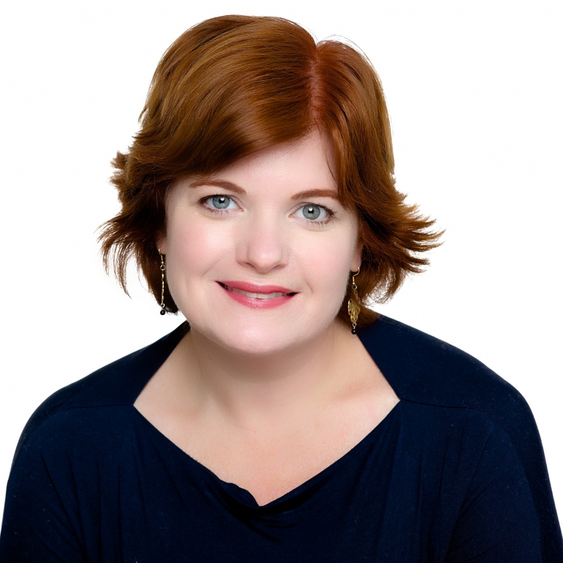 A woman with red hair looks into the camera