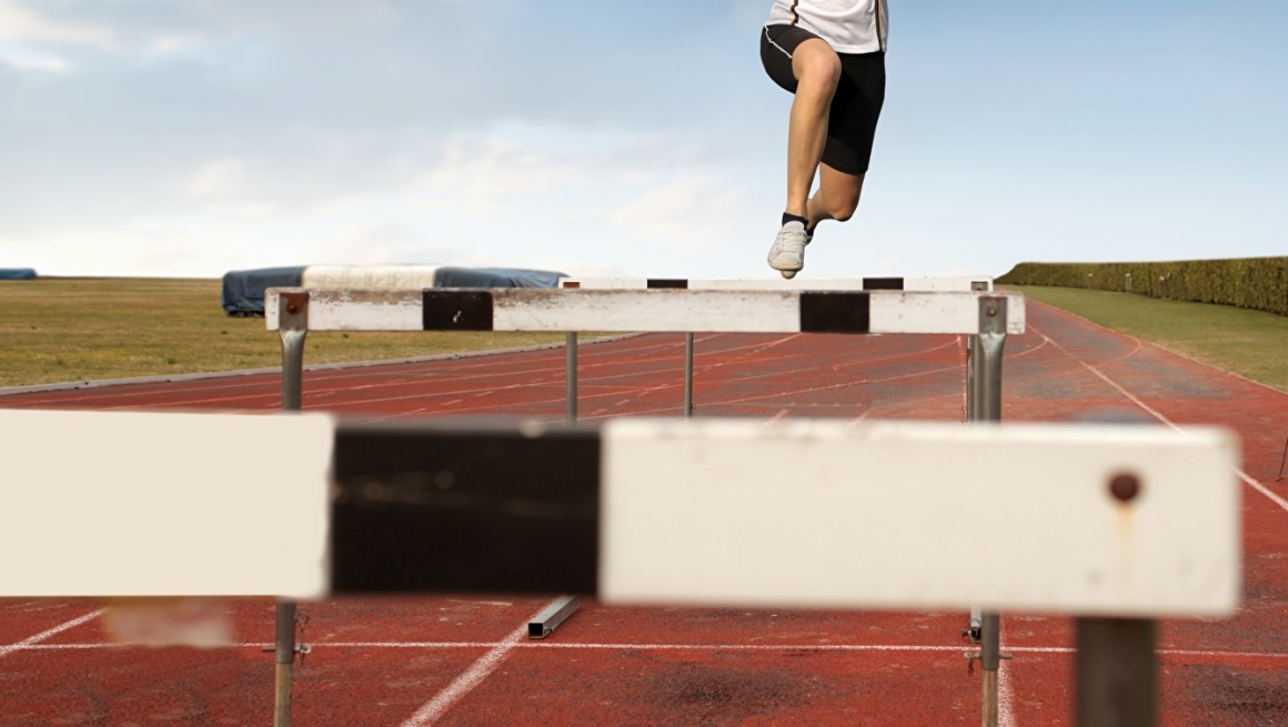 A young woman jumps over obstacles on a racetrack