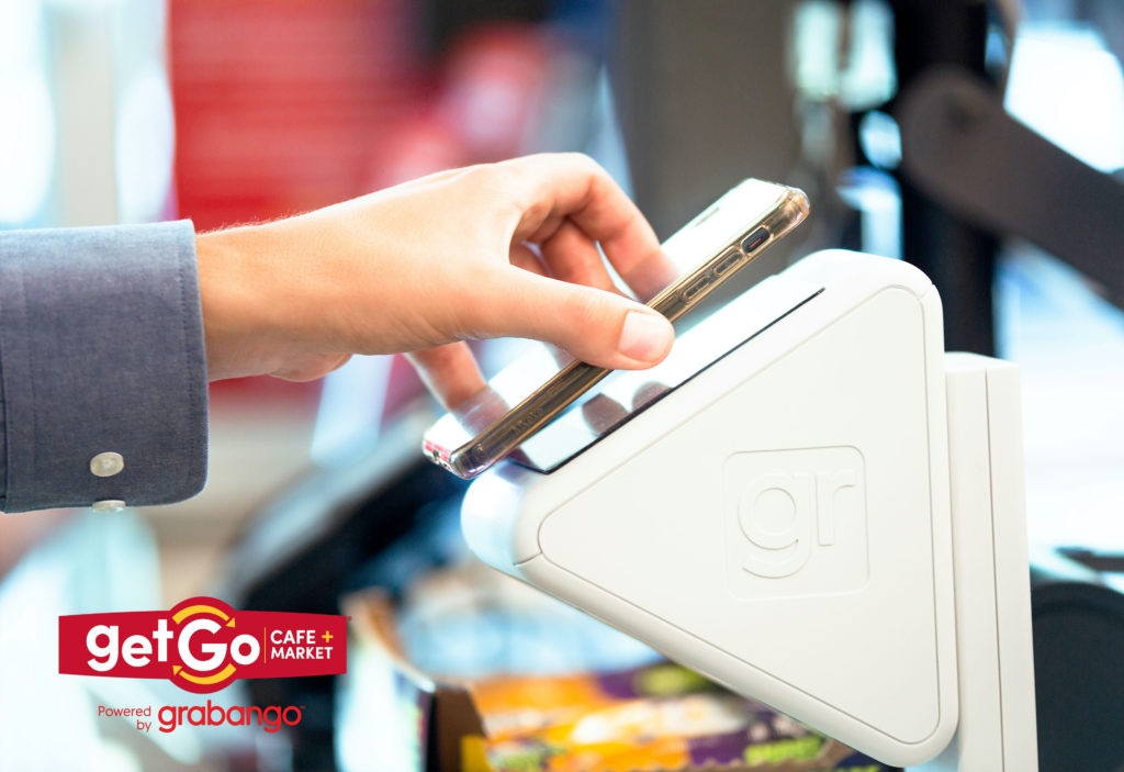 A hand holding a smartphone to a checkout device