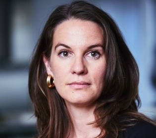 Woman with dark long hair looks into the camera