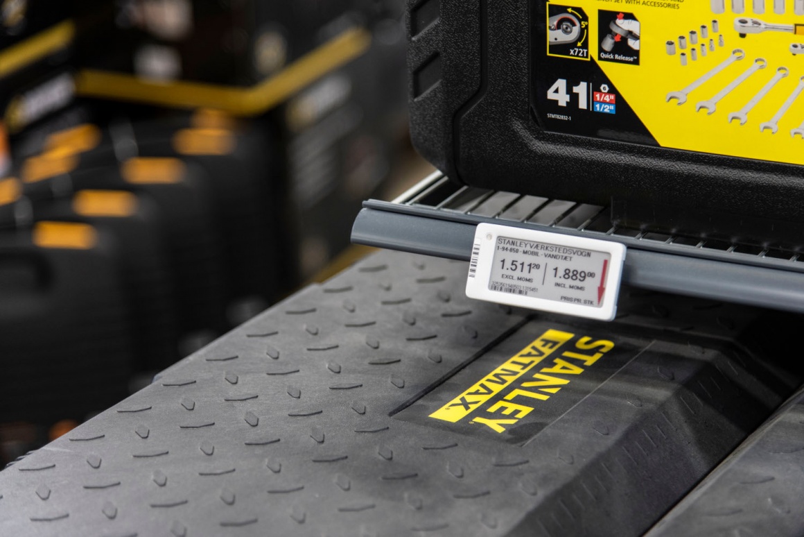 An electronic price tag on a shelf in a hardware store with a toolbox...