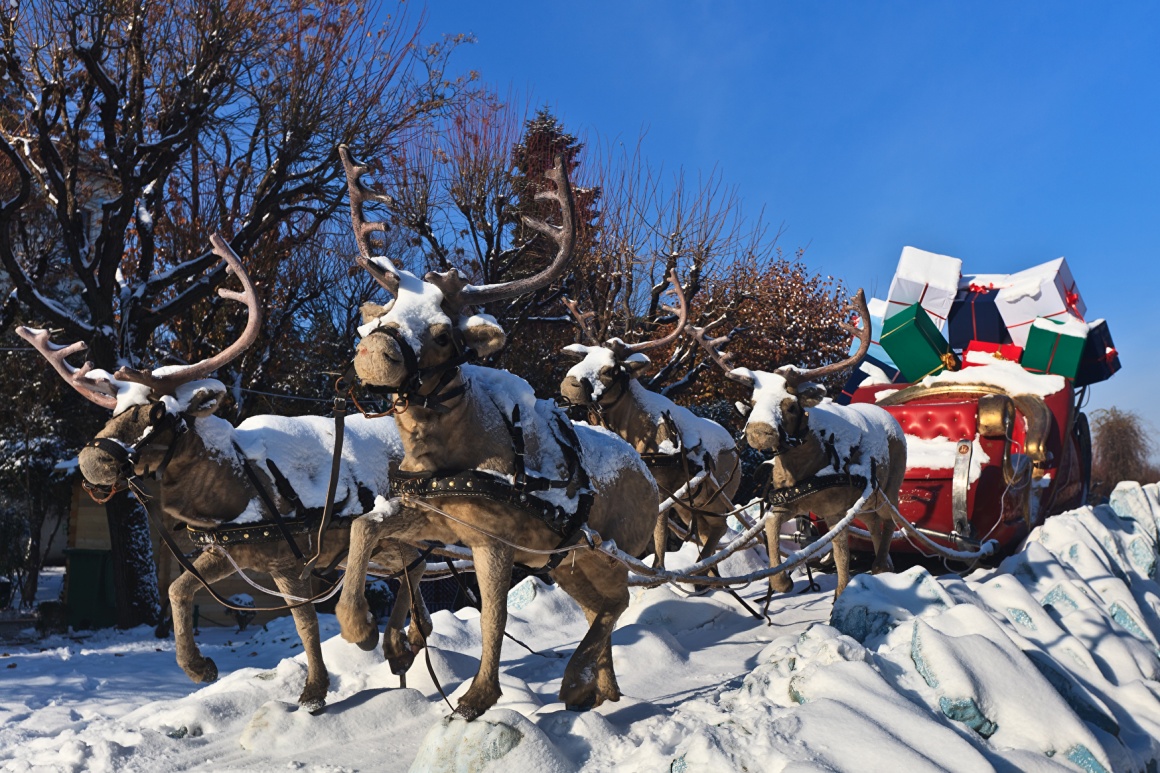 reindeer pull a carriage full of huge gifts through the snow...