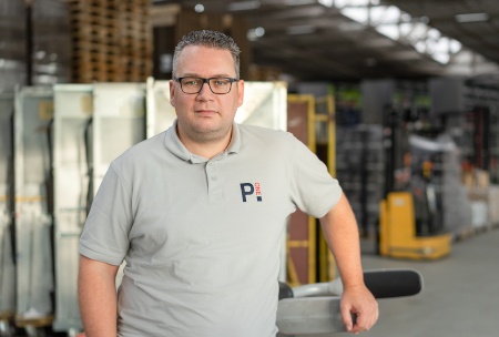 A man in a polo shirt and with glasses in a warehouse...