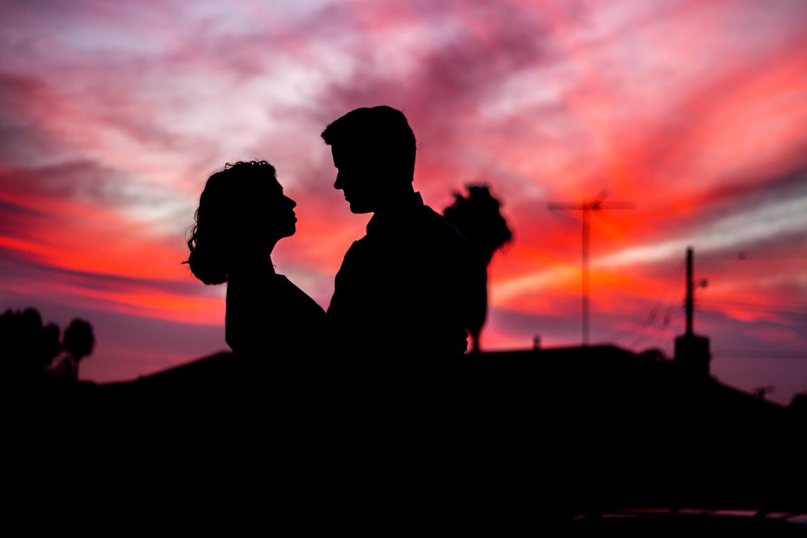 The dark silhouettes of a woman and a man in front of a red sunset...