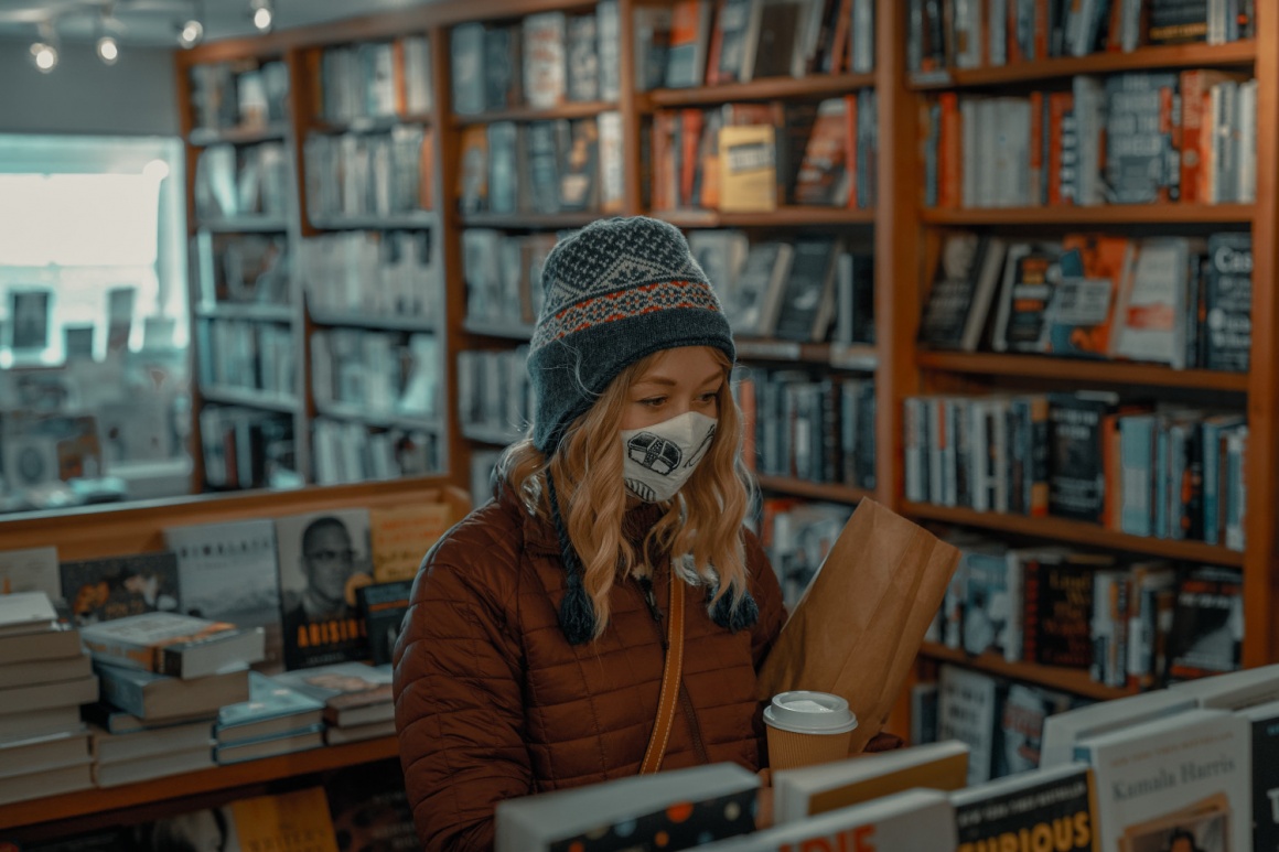 A woman wearing a mask shopping in a book store; copyright: Clay Banks/Unsplash...