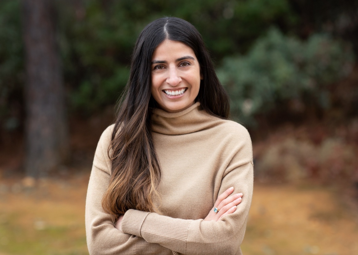 A young woman with long brown hair smiling into the camera...