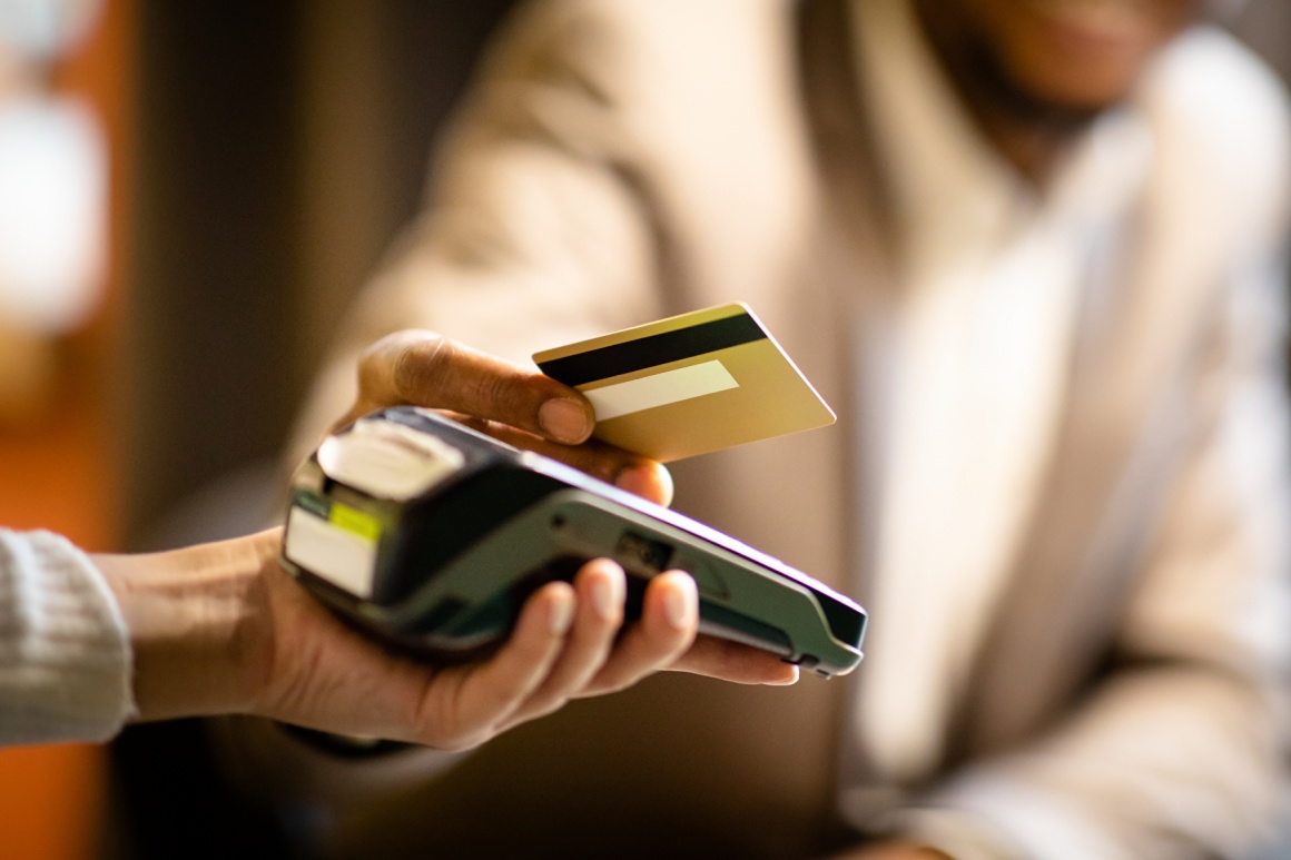 hand holding a credit card over a payment device