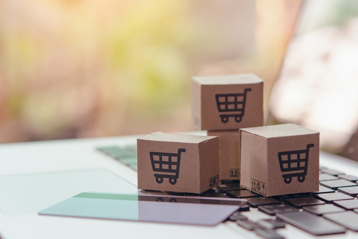 three litte boxes with a shopping cart icon lay on a keyboard next to a credit...